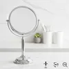 A silver makeup mirror on a white countertop with a marble pattern. Produktbild-Vorschau