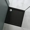 A close-up view of a black square shower tray with a silver drain cover, set in a modern bathroom with gray tiled walls. Produktbild-Vorschau