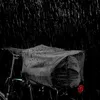 A black bicycle bag covered in raindrops, attached to a bicycle rack, with rain falling in the background. Anteprima dell’immagine prodotto