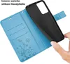 A hand is holding a black phone case over an open blue wallet-style phone case with card slots and embossed floral and butterfly designs. Produktbild-Vorschau