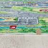 A close-up view of a colorful children's play rug depicting a city street scene. Produktbild-Vorschau