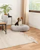 A beagle dog sits in a round, plush dog bed in a living room setting. Anteprima dell’immagine prodotto