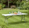 A white folding table set up in a grassy backyard with drinks and food on it, and a wooden bench in the background. Produktbild-Vorschau