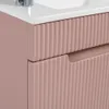 A close-up view of a pink bathroom vanity with fluted drawers and a white countertop with a faucet. Voir les images du produit