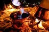 Two copper pots are being heated over a fire, with flames and embers visible. Produktbild-Vorschau