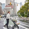 A woman pushes a stroller down a city street. Náhled obrázku produktu
