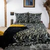 A bed with black and gold floral patterned bedding, a black fluffy throw blanket, and a yellow throw blanket. Podgląd zdjęcia produktu