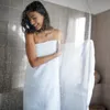A woman wrapped in a towel stands behind a shower screen with water droplets on it. Produktbild-Vorschau