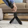 A hand using a cleaning tool to spray liquid onto a carpet. Anteprima dell’immagine prodotto
