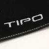 A close-up view of a black car floor mat with white embroidered text. Produktbild-Vorschau