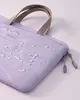 A close-up of a light purple laptop bag with water droplets on it. Náhľad obrázku produktu
