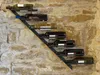 A metal wine rack mounted on a stone wall, holding several bottles of wine. Podgląd zdjęcia produktu