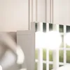 A close-up view of a white vanity mirror with integrated LED lights, reflecting a window with green foliage outside. Produktbild-Vorschau
