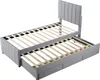 A gray upholstered bed frame with a pull-out trundle bed and drawers, shown from a diagonal angle against a white background. Produktbild-Vorschau