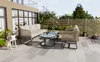 A patio set with a sofa, armchair, and coffee tables on a tiled patio with plants and a fence in the background. Náhľad obrázku produktu