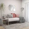 A living room scene with a white metal daybed, decorative pillows, a throw blanket, a plant, and a side table. Podgląd zdjęcia produktu