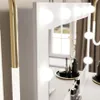 A close-up view of a white vanity table with illuminated bulbs and makeup products. Náhled obrázku produktu