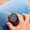 A person wearing a watch and jeans. Voir les images du produit
