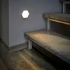 A hexagonal LED light is mounted on a wall next to a carpeted staircase. Produktbild-Vorschau