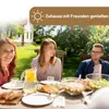 People enjoying a meal outdoors in a garden setting. Produktbild-Vorschau
