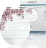 A toilet seat with a floral and wood design is shown next to its packaging. Náhled obrázku produktu