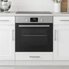 A built-in oven integrated into white kitchen cabinetry, with a modern induction hob visible above it. Náhľad obrázku produktu