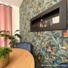 A modern living room with a bioethanol fireplace on a wall with tropical-themed wallpaper. Náhled obrázku produktu