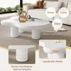 A white, cloud-shaped coffee table is shown in a living room setting with a couch in the background. Inset images highlight the table's features. Produktbild-Vorschau