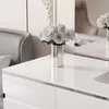 A white desk with a silver vase of white roses. Produktbild-Vorschau