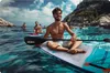 A group of men paddleboarding in a clear blue ocean with rocky cliffs in the background. Náhled obrázku produktu