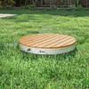 A circular wooden platform with a white base sits on a green lawn. Produktbild-Vorschau
