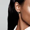 Close-up of a person's ear wearing a silver hoop earring. Voir les images du produit