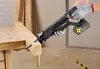 A person wearing work gloves is using a cordless reciprocating saw to cut a wooden beam on a workbench. Produktbild-Vorschau