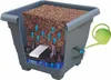 A cutaway diagram of a self-watering planter, showing the internal structure and water flow, with a watering can pouring water into it. Náhled obrázku produktu