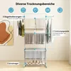 A multi-tiered drying rack with clothes and towels on it, and shoes on the bottom shelf, set against a plain wall. Voir les images du produit