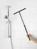 A hand holding a squeegee with a telescopic handle in front of a tiled shower wall with a shower head. Podgląd zdjęcia produktu