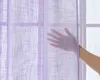 A hand is shown touching a sheer purple curtain in front of a window. Produktbild-Vorschau