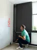 A man is crouching in a room, looking up at a laser measuring device that is projecting a red line on the wall. The device is measuring the height of the wall, which is indicated as 2.520 m. Produktbild-Vorschau