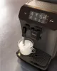 A close-up shot of a Philips coffee machine frothing milk into a glass cup. Produktbild-Vorschau