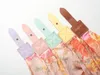 A close-up, diagonal view of the top portion of several umbrellas, each with a different colored strap and a floral pattern. Produktbild-Vorschau