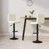 Two cream-colored bar stools are placed around a wooden table with black legs, in a room with light-colored walls and wooden flooring. Náhled obrázku produktu