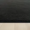 A close-up, low-angle view of a black rug with a textured surface, resting on a light-colored wooden floor. Produktbild-Vorschau