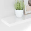 A white floating shelf with a potted plant and a framed picture on it, against a white wall. Náhľad obrázku produktu