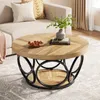 A round coffee table with a wooden top and a black metal base is placed in a living room setting. Produktbild-Vorschau