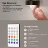 Schwarze LED-Wandleuchte an einer Wand montiert, eine Hand berührt sie, mit einer weißen Fernbedienung und Funktionsbeschreibungen Náhled obrázku produktu