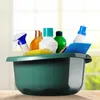 A collection of cleaning supplies in a green basin, set against a blurred background of a window and greenery. Anteprima dell’immagine prodotto