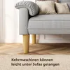 A close-up view of the lower part of a gray sofa with wooden legs, placed on a wooden floor and a rug. Text is overlaid on the rug. Produktbild-Vorschau