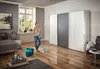 A woman is mopping the floor in a bedroom with a modern wardrobe and bed. Produktbild-Vorschau