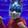 A child wearing an Optimus Prime mask and a red shirt, with fists raised, in front of a blue background. Anteprima dell’immagine prodotto