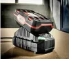A black and red battery charger with a green indicator light is shown on a wooden surface. Produktbild-Vorschau